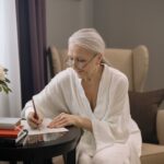 elderly woman in write robe writing her will